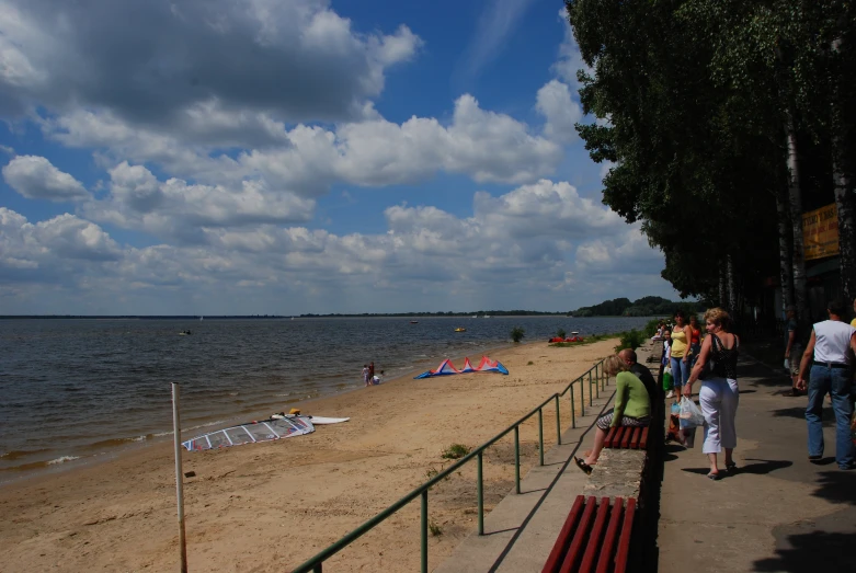 people stand on the sidewalk looking out over a beach