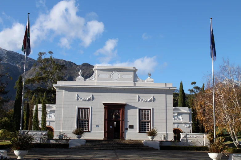 a white and grey building with two flags and a building sign