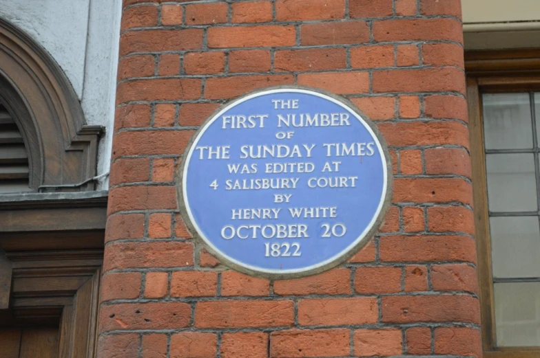 blue plaque on the side of a brick building