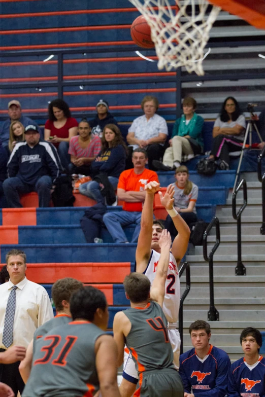 people watching a game of basketball being played in a gym