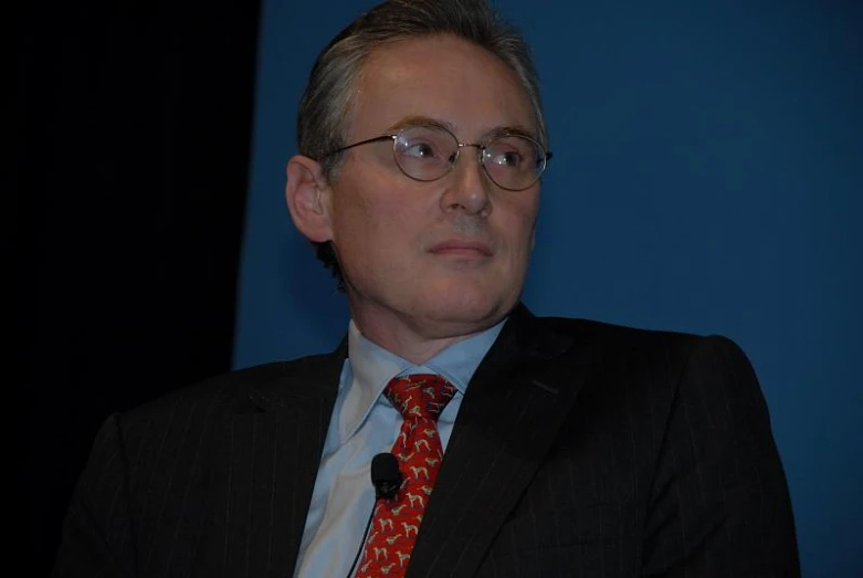 a man in glasses and a red tie is sitting down