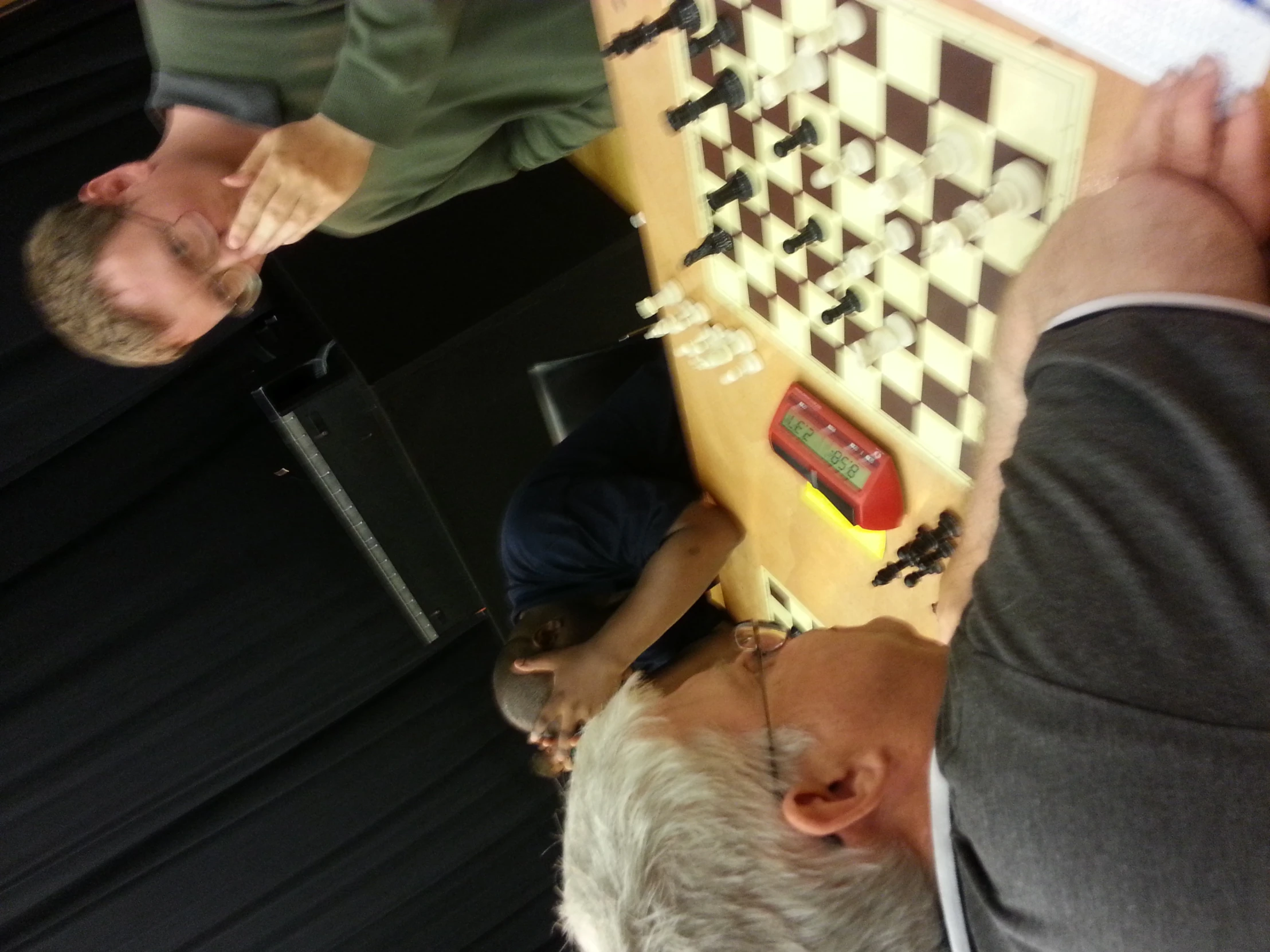 two men play chess together at a table