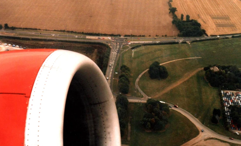 an aerial view of farmland with a red wing on a jet