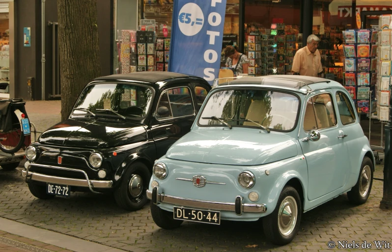 two antique cars are parked next to each other