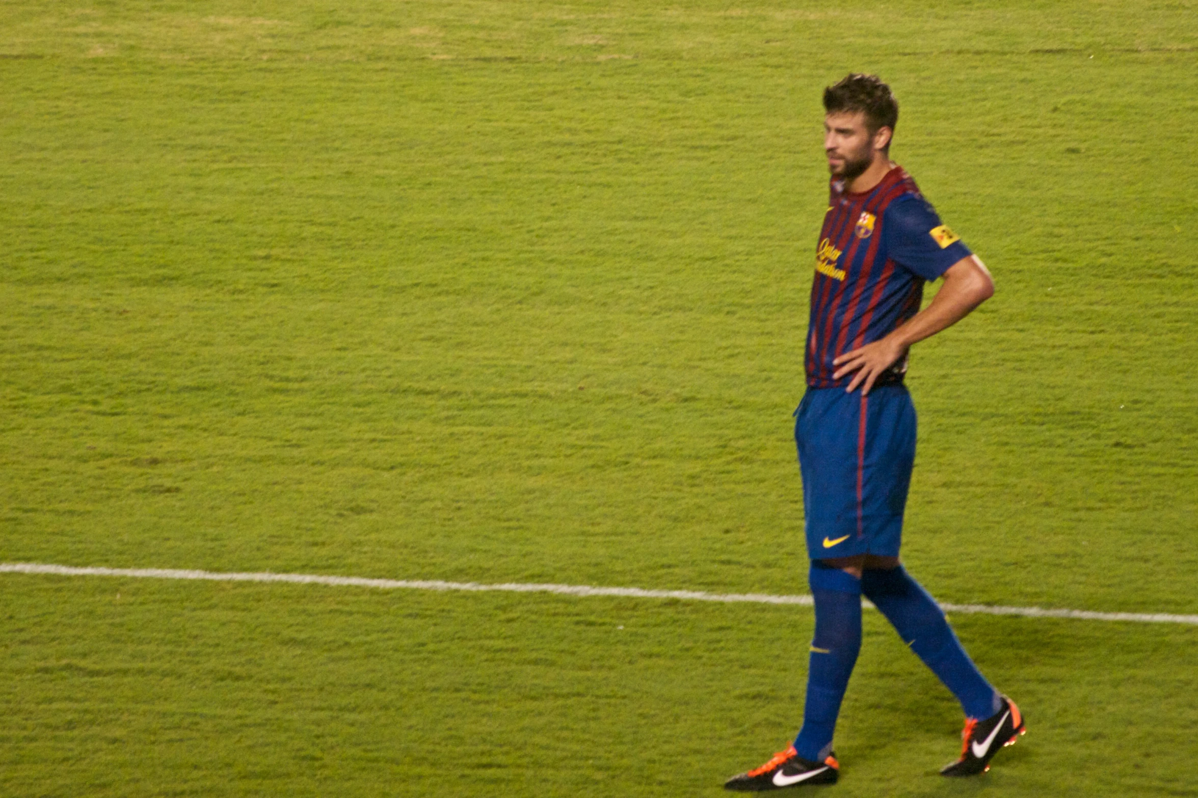 a young man walking across a lush green soccer field