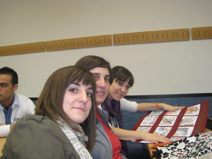 three people sitting on the couch posing with a large blanket