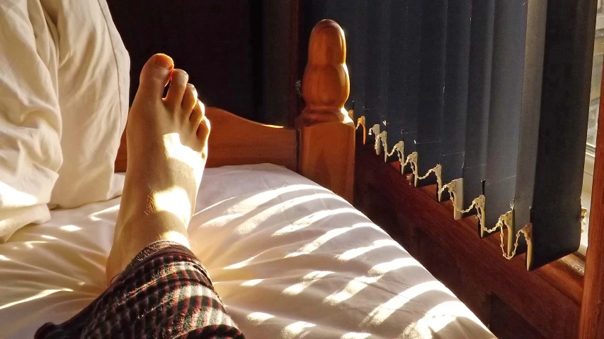 a person's foot laying on top of a bed with white sheets