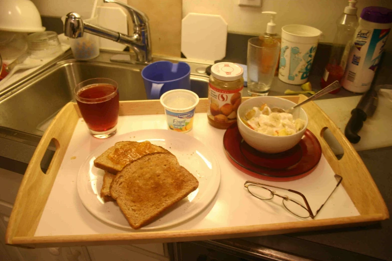 a wooden tray with bread and coffee on top of it