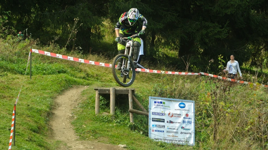 a downhill cyclist on his bike riding over a jump