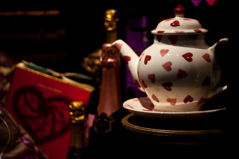 a white tea pot with a heart design is placed on a gold plate