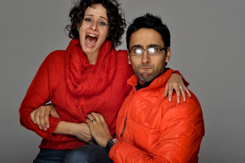 the man and woman are posing together in front of gray background