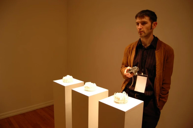 a man standing next to some small sculptures