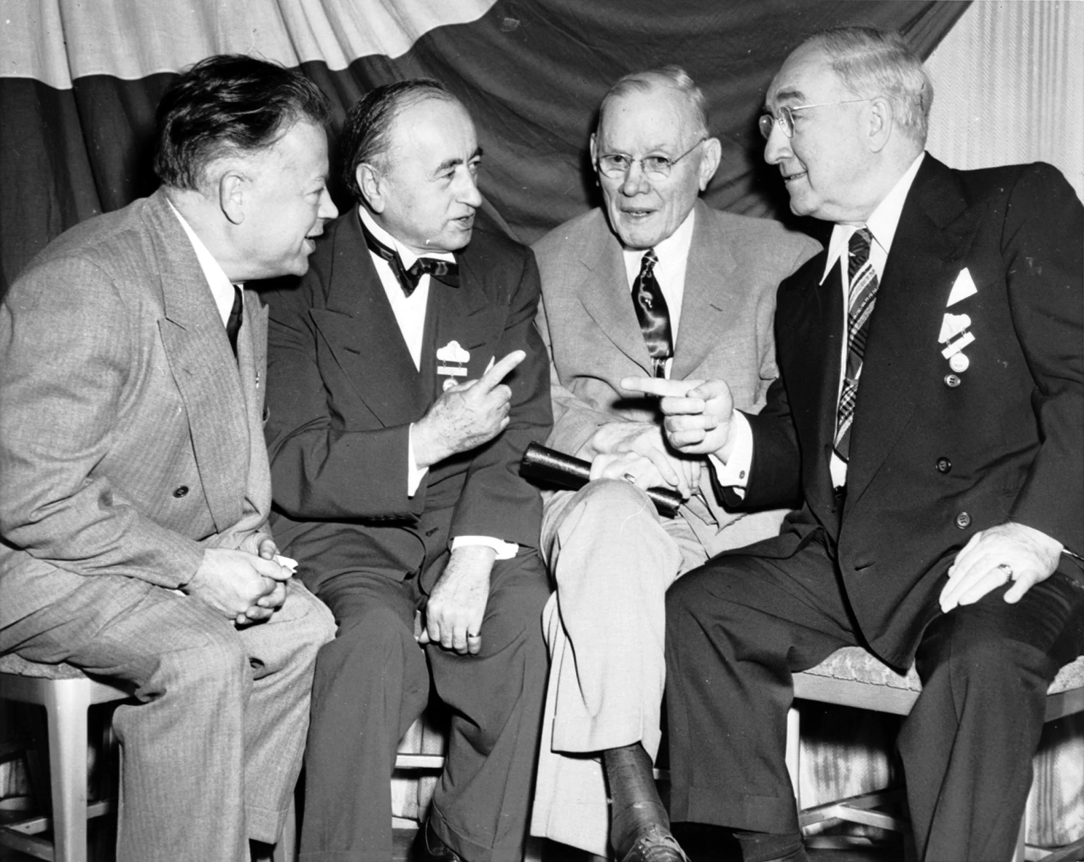 four men in suits and ties are laughing