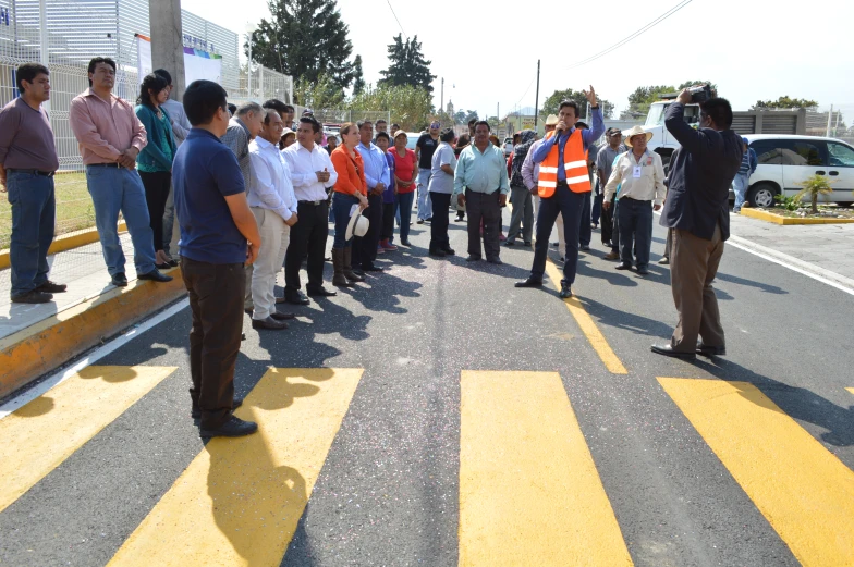 several men stand on the side of a road as one man points to a white van