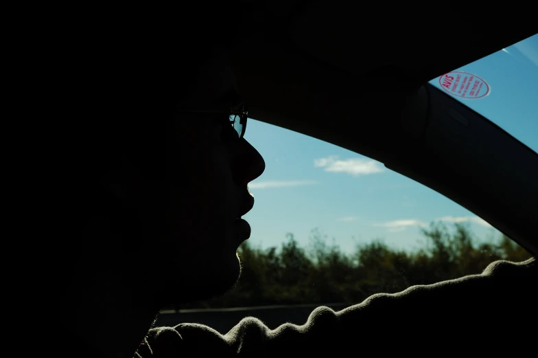 a man with glasses looking out the window in the back of a car