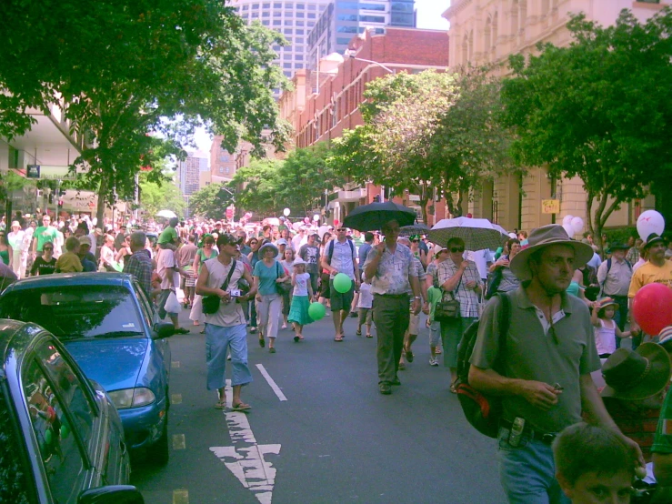 many people are walking down the street with umbrellas