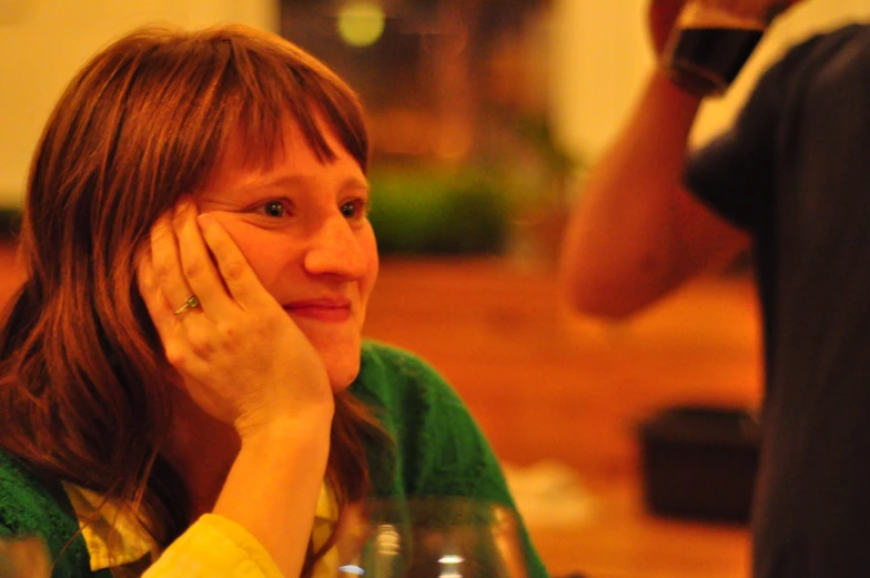 woman at table with glass looking concerned as she listens to someone