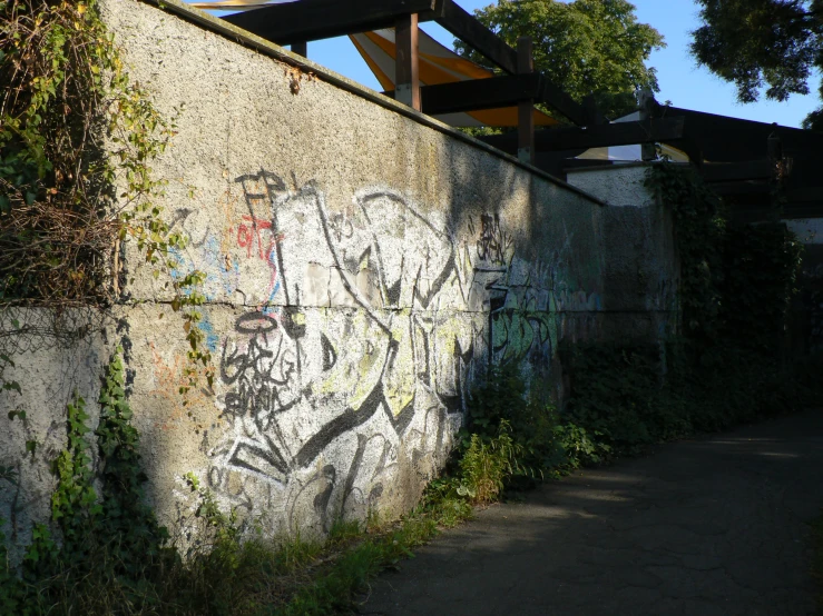 a wall with graffiti and a rail bridge