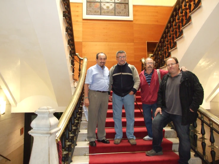 three men are standing on the red carpeted staircases