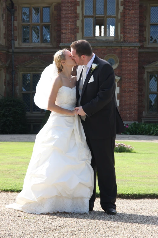 a bride and groom kissing with a house behind them