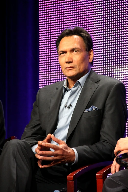 a man wearing a suit sitting down in a chair