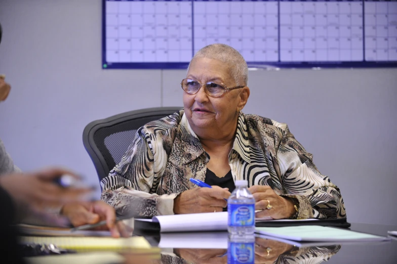 an elderly person sitting at a table with papers