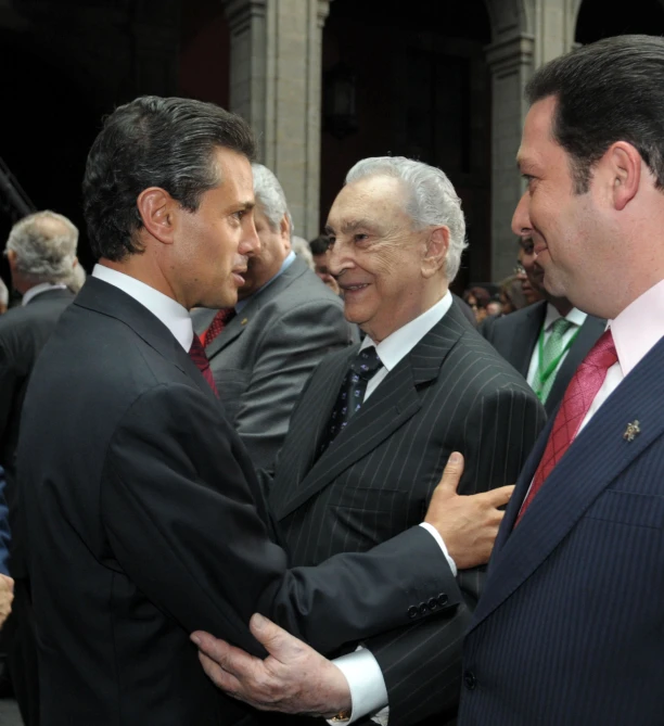 two men are shaking hands as others stand around