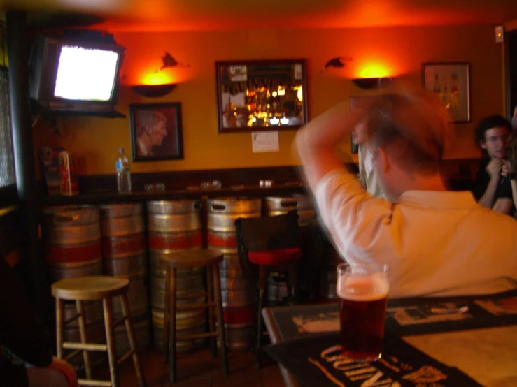 a man in white shirt at a bar with people watching