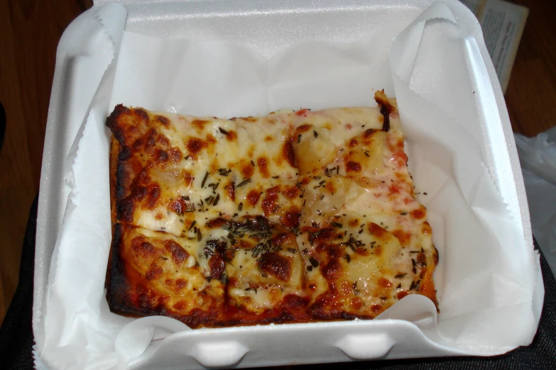 one square slice of pizza in a white container