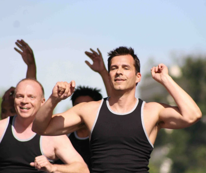two men wearing tank tops, one with a fist raised in the air