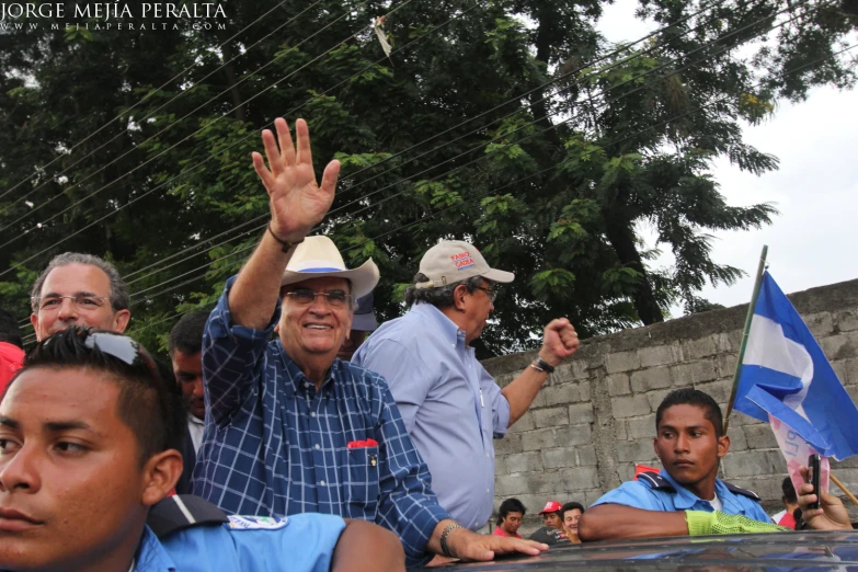 men are waving from the back of a car