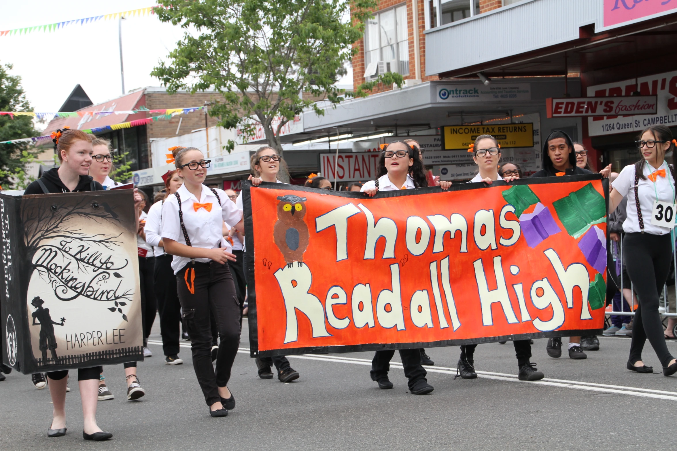 a group of girls walking down the street holding a sign