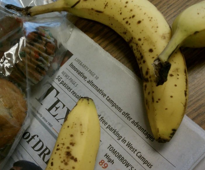 two bananas are laying on top of newspaper