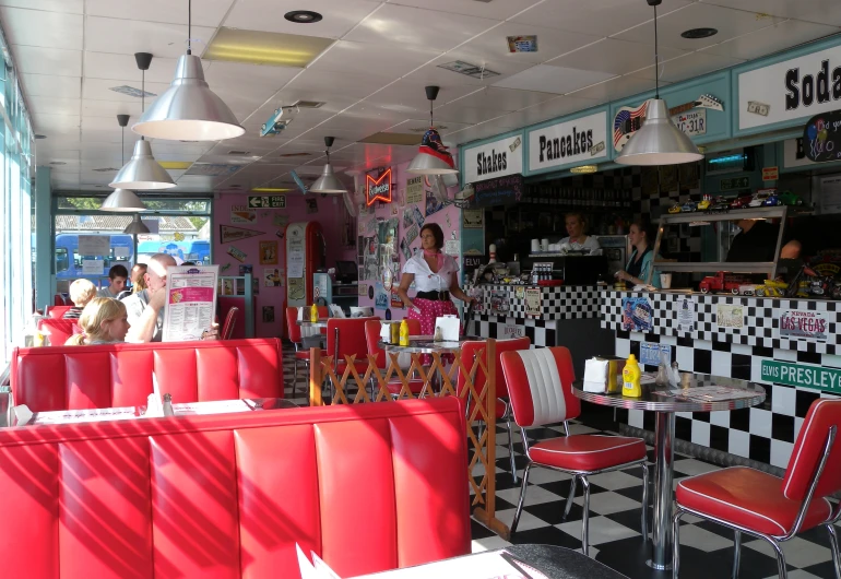 customers sitting at red booths and black and white checkered tablecloth