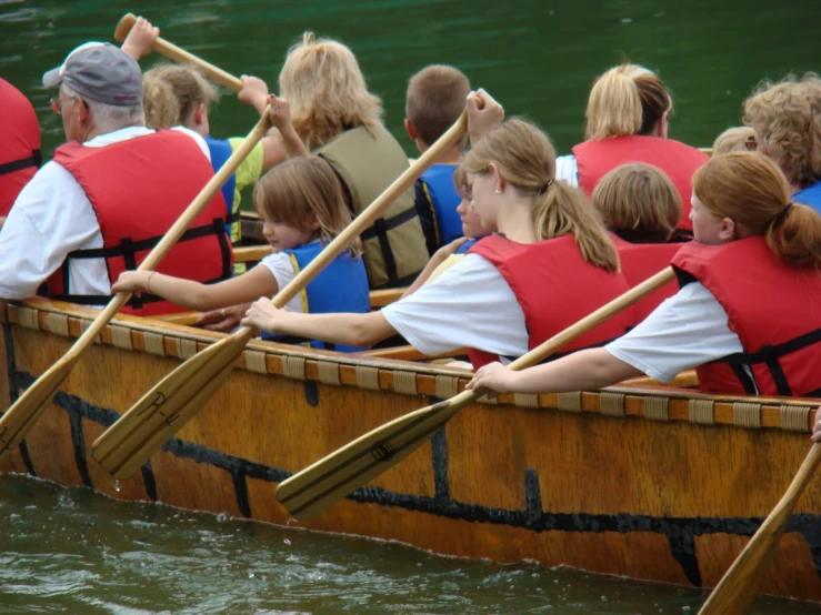 people in canoes row with paddles on the water