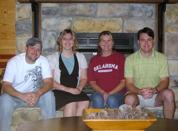 some people sitting and smiling in front of a fireplace