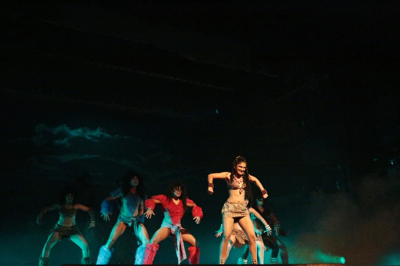 group of dancers on stage with neon lights and dark sky