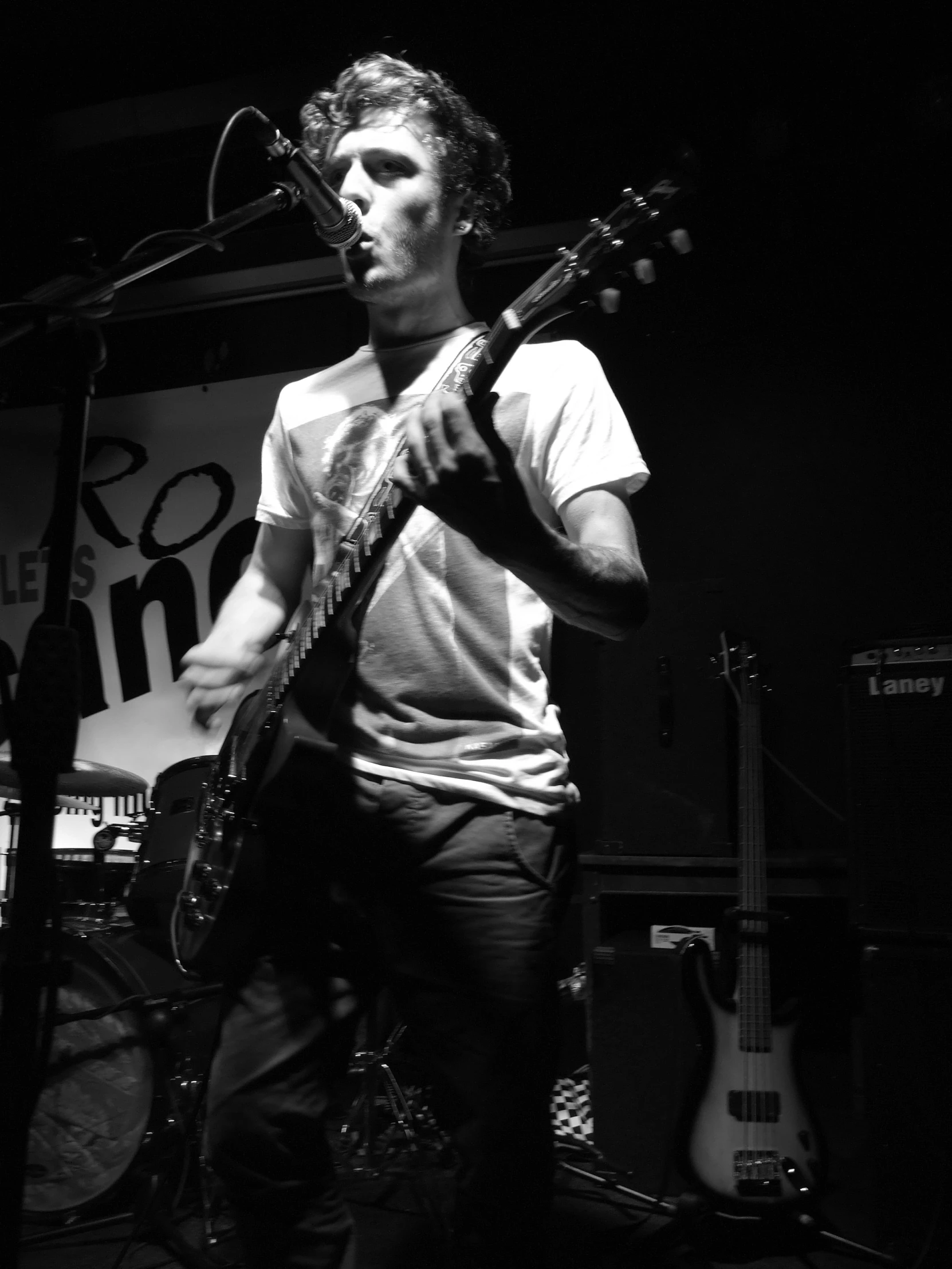 a man is playing guitar and standing in front of a microphone