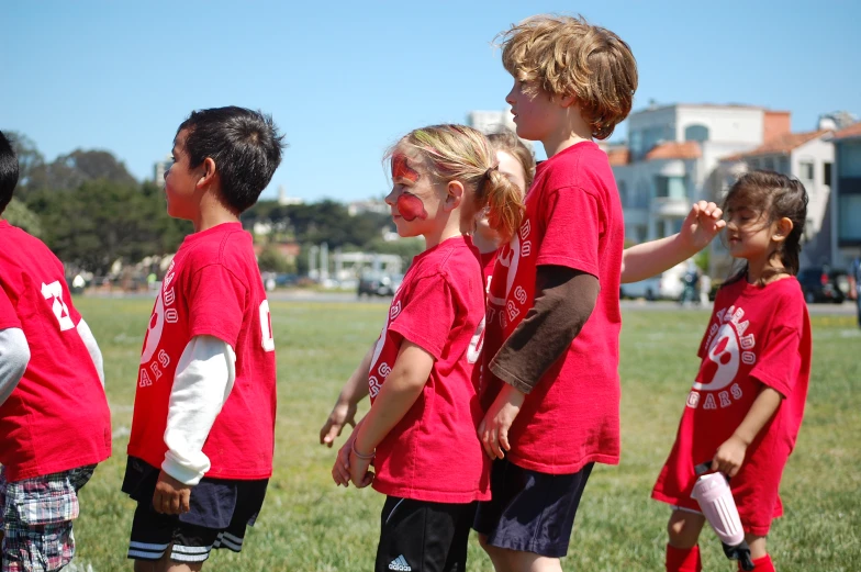 four s are wearing red shirts as they hold hands in a circle