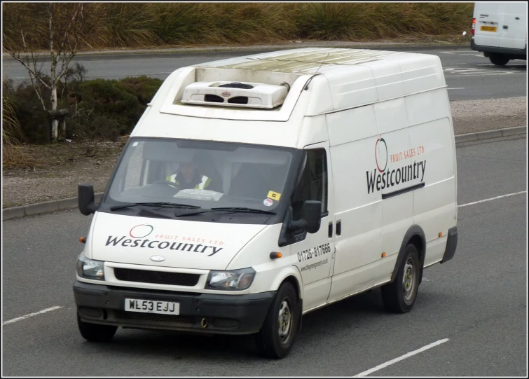 a van with the name westcounty is driving down the road