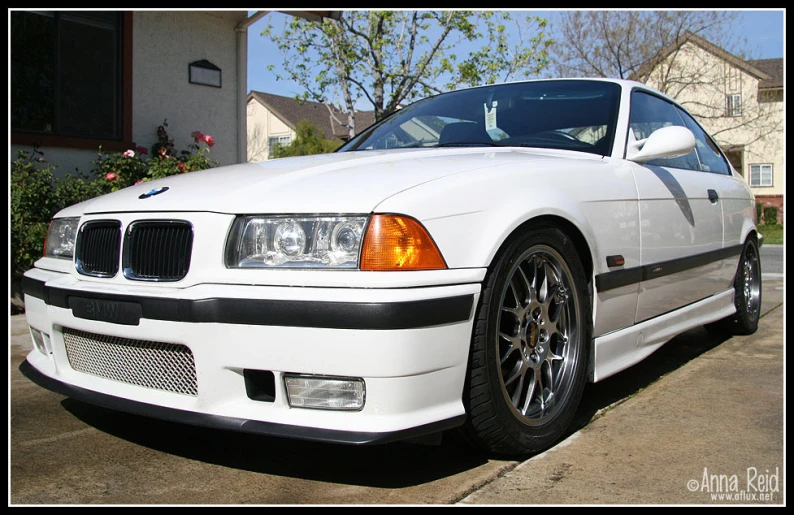 white bmw coupe parked in a driveway on the road