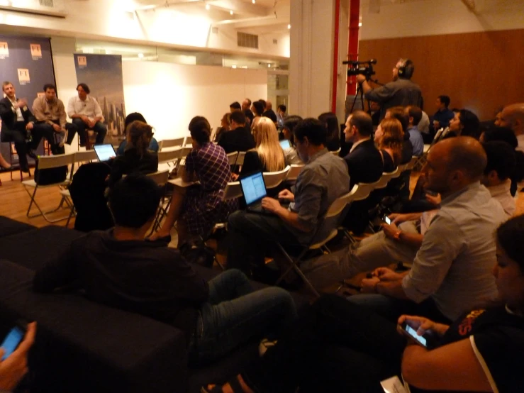 several people are sitting in chairs as the presenter talks to them