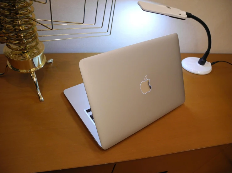 the apple laptop is sitting on the desk near the lamp