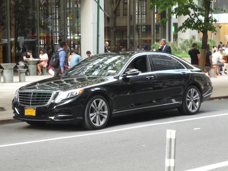 black car driving down a city street in front of a store