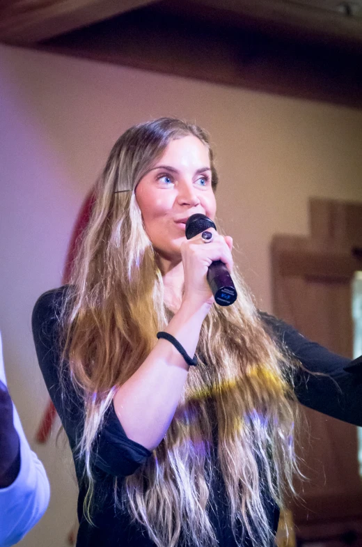 a girl singing with a microphone and holding soing in her hands