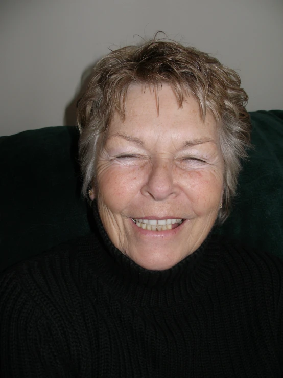 a smiling woman in a black sweater on a couch