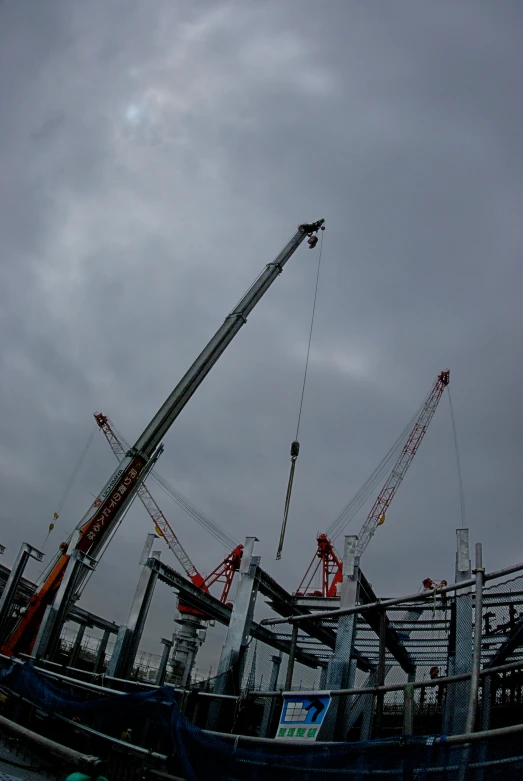 two cranes are sitting over the building under construction