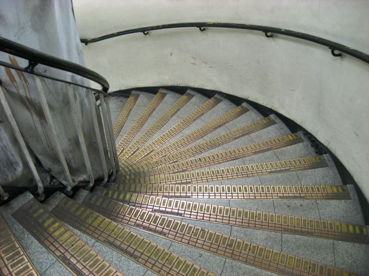 a curved metal spiral staircase with yellow and brown treads