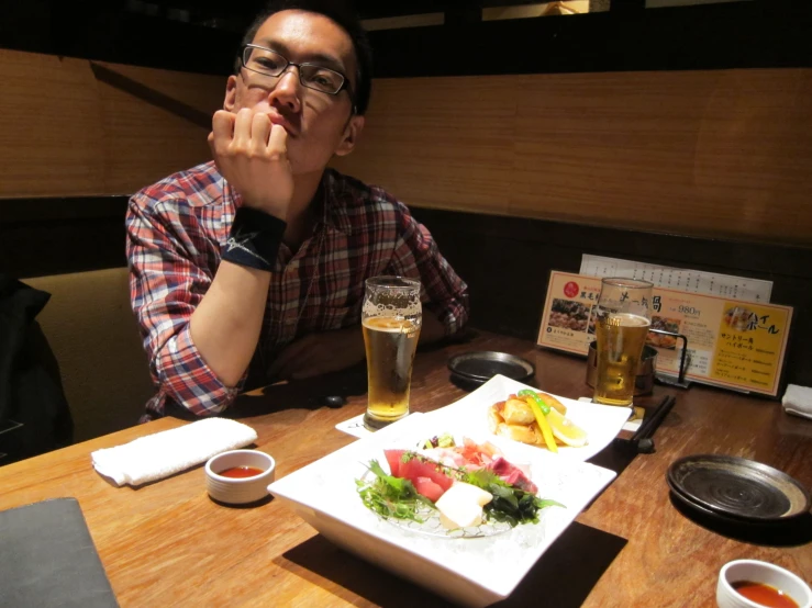 a man is sitting at a table with plates and drinks