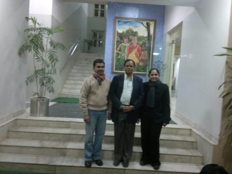 four people standing in front of a painting on a wall